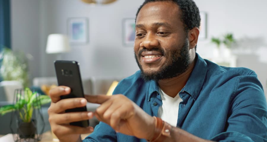 Man at home using a home security app on his cell phone