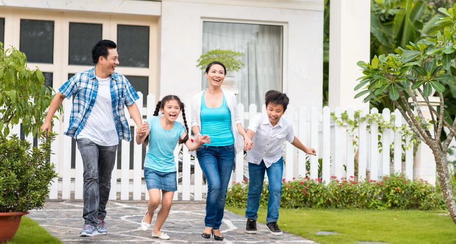 Family holding hands and walking away from a nice home with a white fence